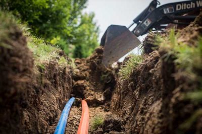 Laying fiber optic cable during a fiber construction project with used capital equipment.